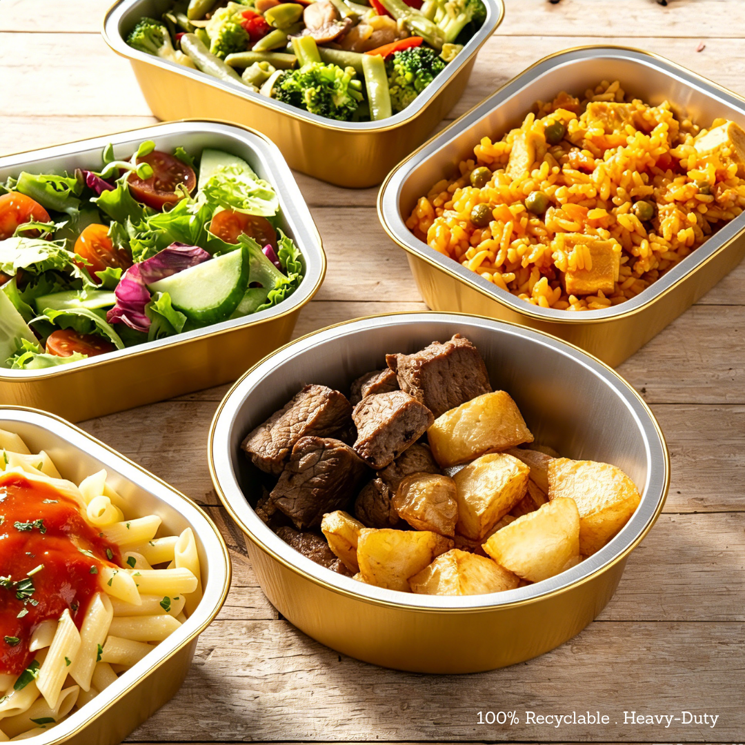 Various shapes of premium gold aluminum foil food containers from Foiltrust, featuring a heavy-duty, 100% recyclable design holding assorted hot and cold meals.